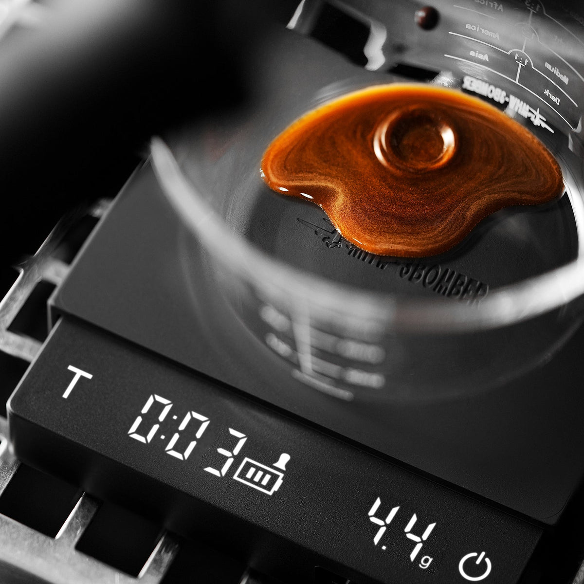 A close-up of coffee being poured into a glass on the MHW-3BOMBER Cube Coffee Scale 3.0 Micro, which displays a timer and a weight reading of 4.4 grams.