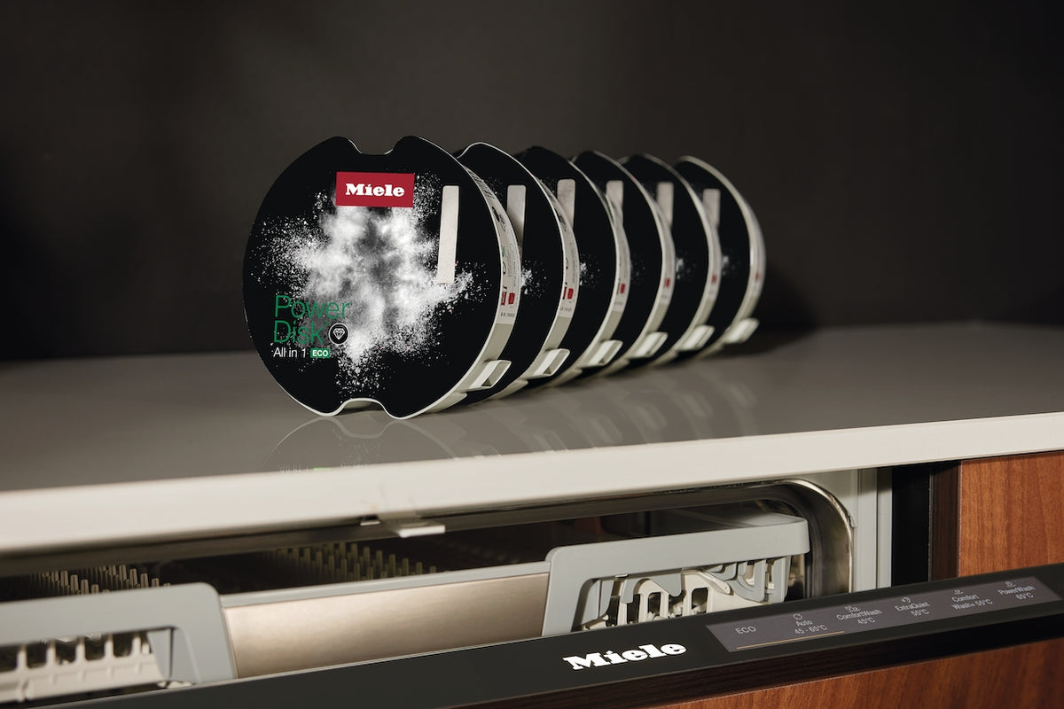 Miele PowerDisk All in 1 ECO disks beside an AutoDos dishwasher