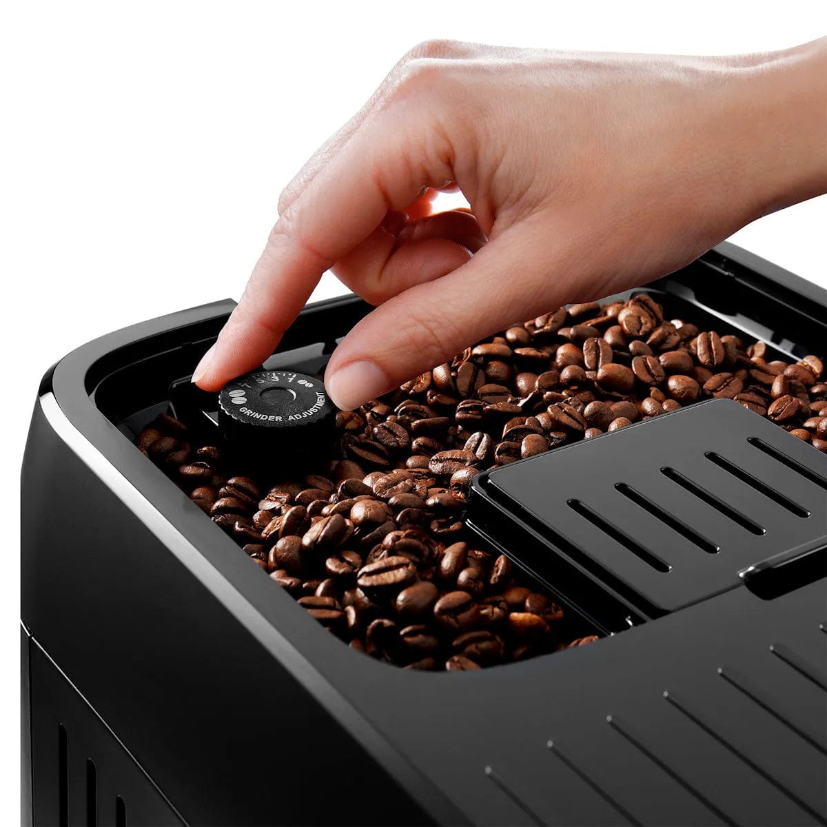 A hand adjusts a dial on the DeLonghi Magnifica Plus Super Automatic Espresso Machine with LatteCrema System ECAM32070SB, which features integrated grinding technology for fresh coffee drinks every time.