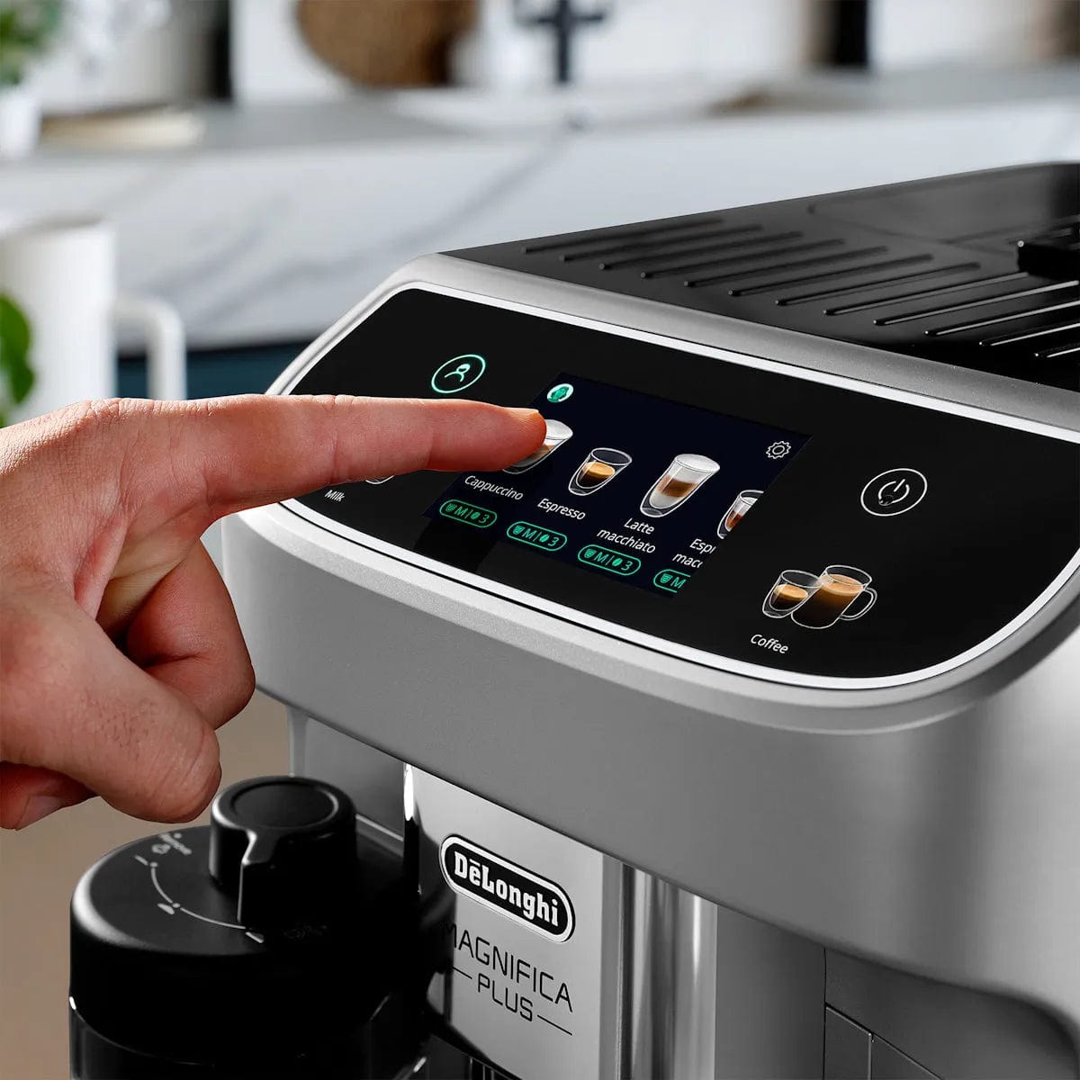 A hand presses a button on the DeLonghi Magnifica Plus Super Automatic Espresso Machine ECAM32070SB, choosing espresso or cappuccino made with integrated grinding and the LatteCrema System.