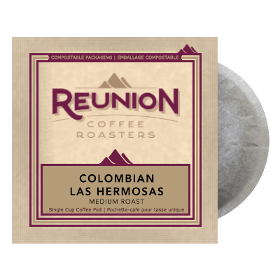 A coffee pod package from Reunion Coffee Roasters, labeled "Reunion Coffee Roasters Colombia Las Hermosas Soft Pods." The beige package design, adorned with a maroon logo and mountain illustrations, features Fair Trade Certified text and proudly states it is compostable.
