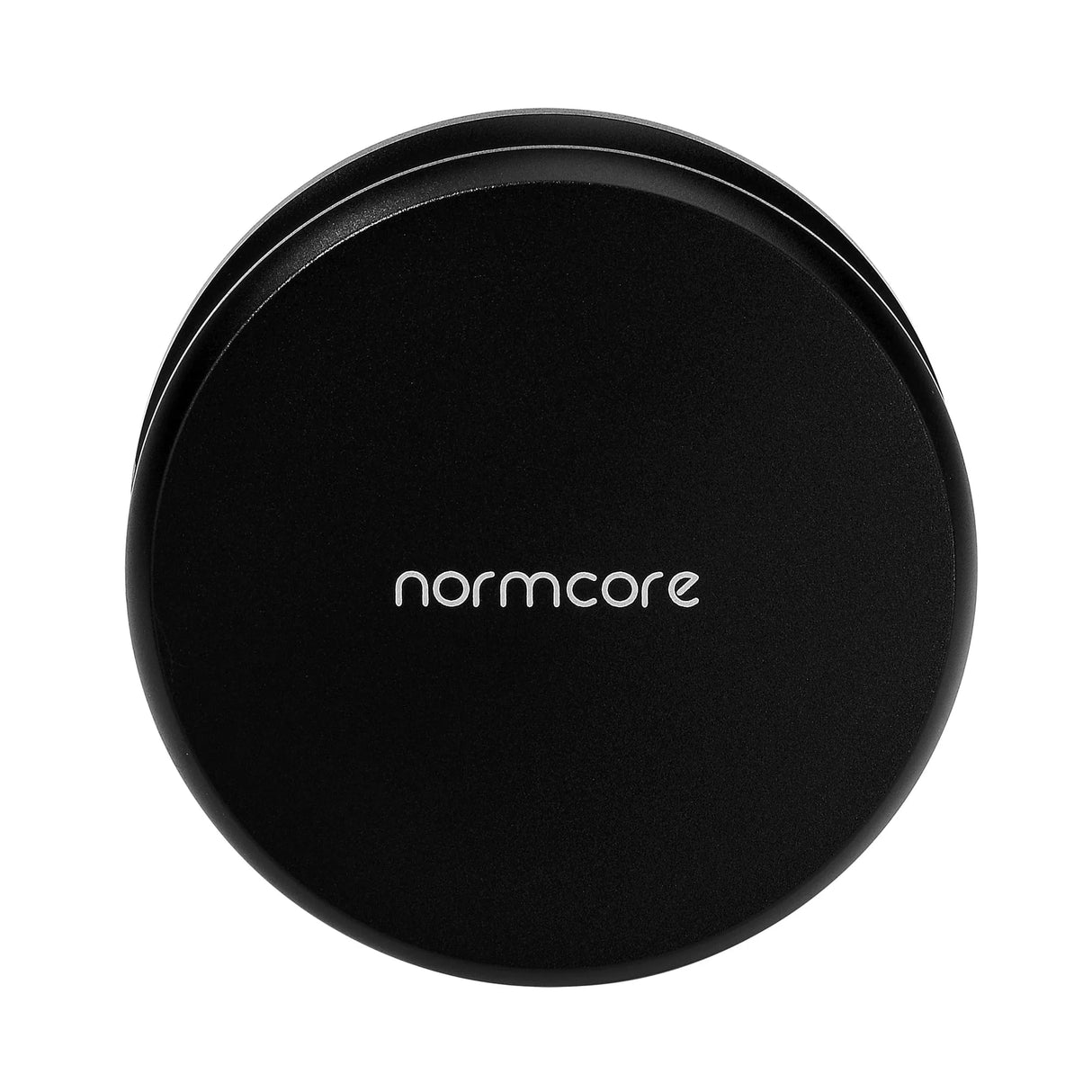 A black, round Normcore Gravity Distributor Tool (58.5mm) with "normcore" in white lowercase letters on top, seen from above against a white background. Perfectly sized to fit a 58.5mm portafilter, this tool by Normcore ensures even coffee grounds distribution for consistent espresso extraction.