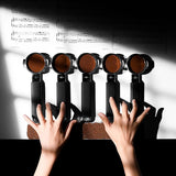Two hands press coffee grounds with the MHW-3BOMBER YU Series Unibody Bottomless Portafilter 58mm, arranged like piano keys beneath sheet music, merging coffee and music while showcasing extraction efficiency.