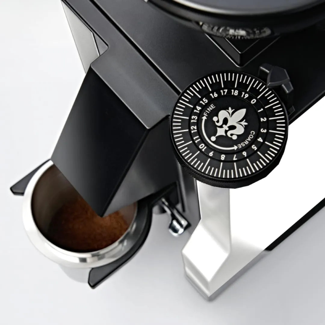 Close-up of the Eureka Mignon Zero 55s Single Dose Coffee Grinder (White) by Eureka, showing its grind size adjustment dial, flat burrs, sleek modern design, and ground coffee falling into a stainless steel container below.