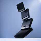 Four black rectangular MHW-3BOMBER Cube Coffee Scale 3.0 Micro devices, featuring illuminated numeric displays and a modern electronic design, are neatly stacked in a slightly tilted arrangement against a light blue gradient background.