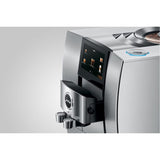 A close-up of the Jura Z10 Aluminum White Super Automatic Hot Coffee & Espresso, Cold Brew, & Specialty Beverage Machine 15361 by Jura highlights its modern silver finish, digital display, dual spouts, and a circular button on top. This advanced machine features a Product Recognising Grinder for optimal coffee quality.