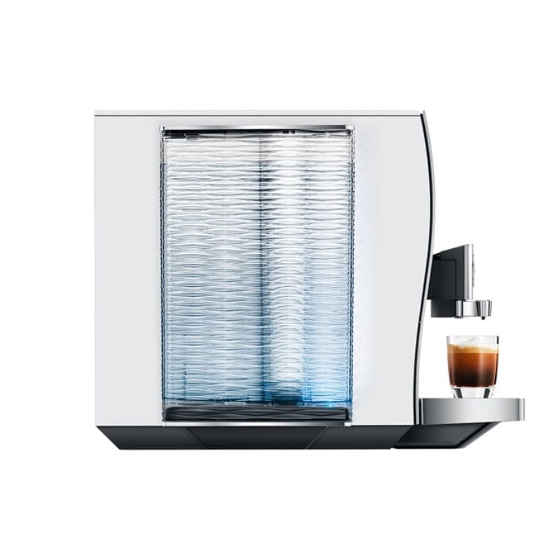 The Jura Z10 Aluminum White Super Automatic Hot Coffee & Espresso, Cold Brew, & Specialty Beverage Machine by Jura, featuring a sleek metallic design and a transparent water tank, is dispensing a shot of espresso into a small glass cup.