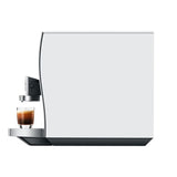 A sleek and modern Jura Z10 Aluminum White Super Automatic Coffee & Espresso Machine (model 15361, Open Box 4982) brews a shot of espresso into a small clear glass cup. Set against a plain white background, the scene highlights the refined minimalist elegance characteristic of Jura craftsmanship.
