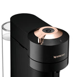 The Nespresso Vertuo Next Premium Coffee and Espresso Machine with Aeroccino by De'Longhi ENV120BAE in black with rose gold features a cylindrical design with a metallic top and rose gold accent. Equipped with Centrifusion Extraction Technology, it offers easy operation through the top button, while the visible left-side water reservoir adds convenience. The prominent Nespresso logo is displayed on the front for added style.