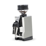 The Eureka Mignon Zero 65 All Purpose Grinder in white offers a sleek, modern design with a metallic finish. Ideal for professional baristas, this grinder features a transparent bean hopper filled with coffee beans on top and includes a stainless steel cup for grounds. Engineered to minimize coffee retention, it is perfect for all brewing methods against a pristine, white backdrop.