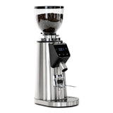 The Bellucci Preciso Mini Coffee Grinder by Bellucci features 64mm flat burrs, a stainless steel body, transparent bean hopper, digital display, control buttons, and a coffee dispensing spout—ideal for home espresso lovers.