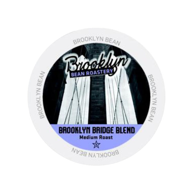 A circular label for Brooklyn Bean's medium roast coffee pods. The text reads, "Brooklyn Bean" at the top and "Brooklyn Bridge Blend Medium Roast Single-Serve Pods" at the bottom over a black-and-white image of the Brooklyn Bridge. "BROOKLYN BEAN" is repeated around the edge. Compatible with Keurig brewers.