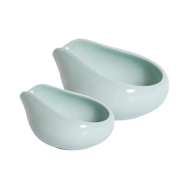 Two celadon blue, glossy ceramic trays with rounded shapes and wide, slanted openings from Loveramics are placed side by side on a white background. Reminiscent of a refined porcelain coffee accessory featured by James Hoffmann, the Loveramics Coffee Dosing Tray Set of 2 showcases one larger and one smaller tray appearing neatly nested together.