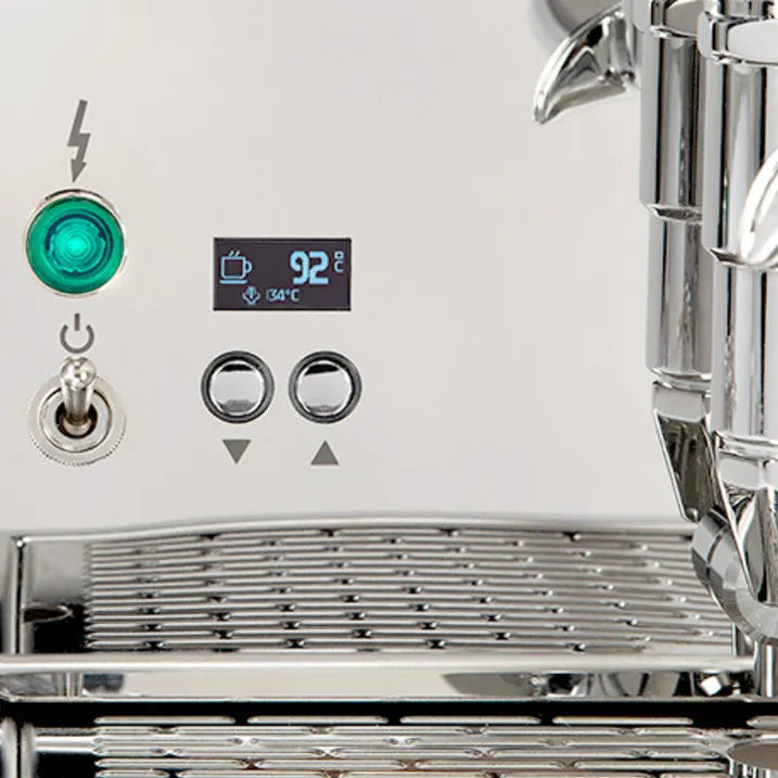 Close-up of the ECM Technika VI Dual Boiler Espresso Machine's control panel by ECM, featuring a green indicator light, on/off switch, arrow buttons, digital PID display at 92°C, and part of the shiny drip tray and portafilter.