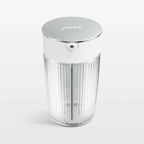 The JURA Glass Milk Carafe 0.5L 24313 by Jura features clear, ribbed borosilicate glass and a shiny metallic lid embossed with "jura," plus a small edge spout, all set against a plain white background.