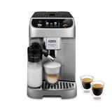 A DeLonghi Magnifica Evo with LatteCrema System (ECAM29084SB) prepares a cappuccino in a glass mug, with two small cups of espresso beside it, all on a white background.
