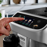 A hand presses a button on the DeLonghi Magnifica Plus Super Automatic Espresso Machine ECAM32070SB, choosing espresso or cappuccino made with integrated grinding and the LatteCrema System.