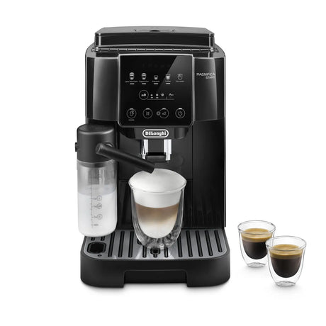 The black DeLonghi Magnifica Start Super Automatic Espresso Machine with LatteCrema System ECAM22080B makes a cappuccino with frothy milk in a glass; two small espresso glasses sit to the right of the machine.