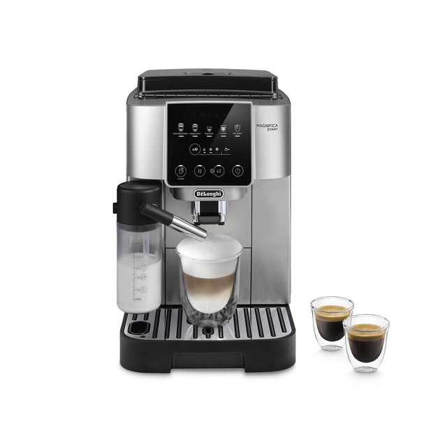 The DeLonghi Magnifica Start Super Automatic Espresso Machine with LatteCrema System ECAM22080SB (Silver) sits on the counter, its sleek silver and black design complemented by a digital display and clearly labeled buttons for various coffee options. Featuring a built-in conical burr grinder to ensure freshly ground beans for each brew, the machine uses its LatteCrema System and integrated milk frother to make a creamy latte, while two small cups of espresso rest beside it.