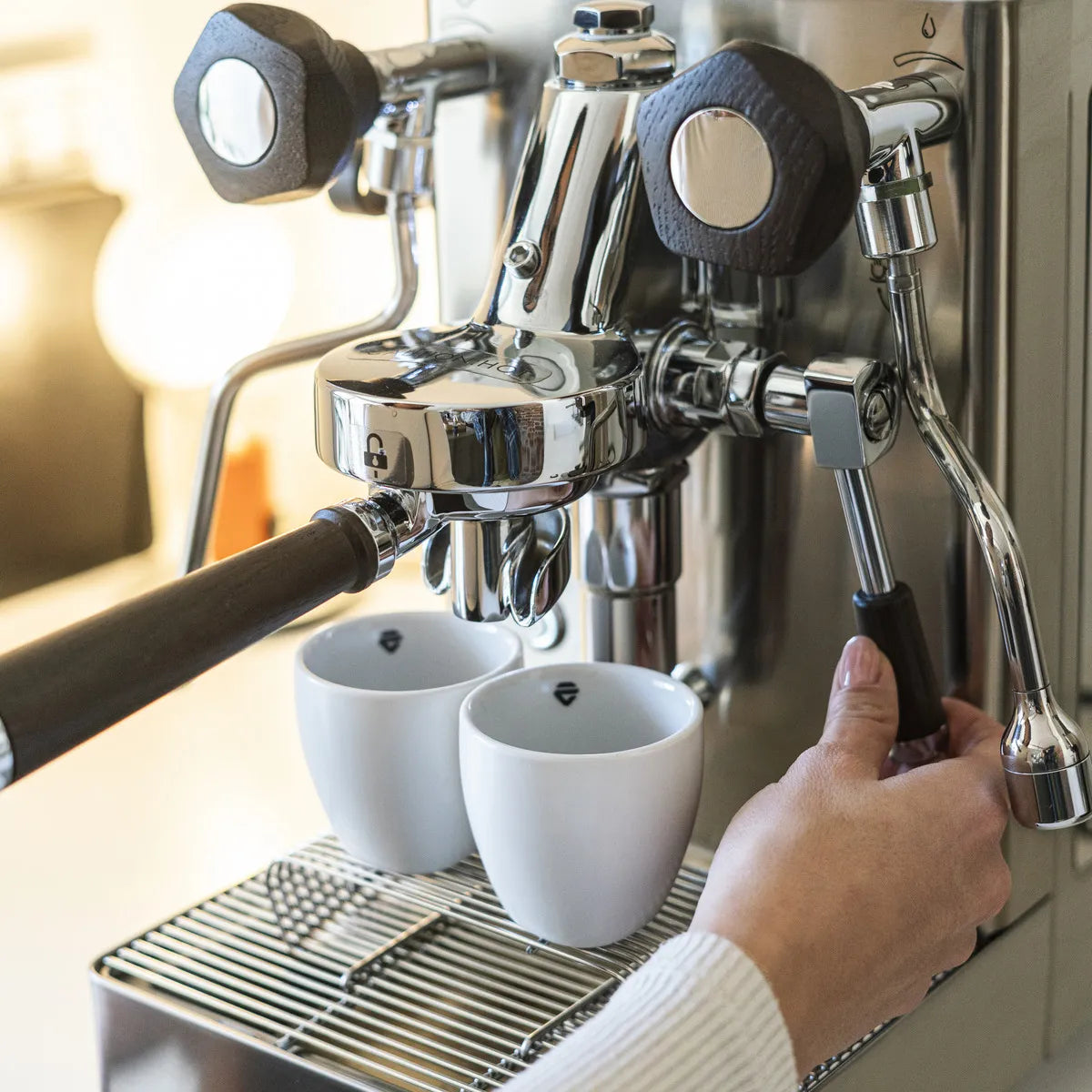 A person uses the Lelit Mara X3 Semi-Automatic Heat-Exchange Espresso Machine PL62X3 (Stainless Steel) to brew coffee into two white cups on the drip tray.
