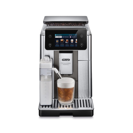 The DeLonghi PrimaDonna Aromatic Super Automatic Espresso Machine ECAM63075TM, with stainless steel finish, digital drink selection display, Bean Adapt tech, Italian flat burr grinder, and left-side milk frother, brews iced coffee into a glass mug.
