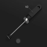 The Subminimal V2 NanoFoamer (Black) by Subminimal is a sleek handheld device with a long metal rod, flat round end, and circular mesh component for perfect microfoam and latte art, shown on a dark background.