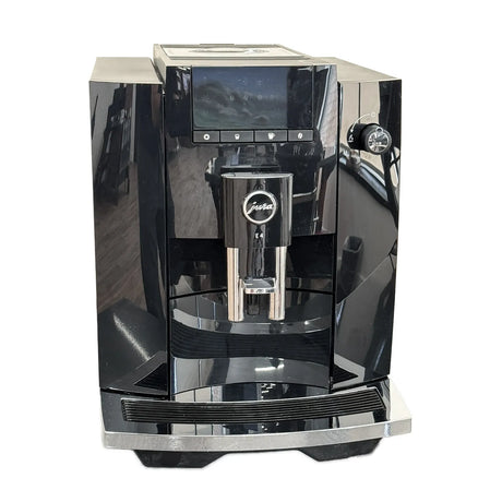 A Jura E4 Super Automatic Coffee Machine 15466 in Piano Black by Jura, featuring a digital display, dual spouts, and the innovative Pulse Extraction Process (P.E.P.), is shown on a white background.