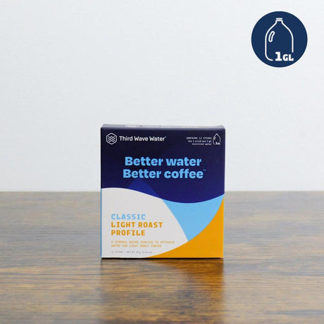 A box of Third Wave Water Classic Profile mineral blend rests on a wooden surface. In blue, yellow, and white hues, it features "Better water, Better coffee" and a 1-gallon jug graphic in the top right corner.