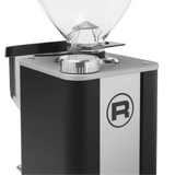 Close-up of the Rocket Giannino Coffee Grinder R01RG099B3A12 by Rocket, featuring a clear hopper, metallic micrometric grind adjustment dial, bold "R" logo, and a sleek black-stainless steel design.