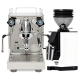 The ECM Mechanika Slim w/ PID Espresso Machine, finished in silver and equipped with dual gauges and PID temperature control, sits beside the Eureka Mignon Zero 55s Single Dose Coffee Grinder in modern white with a black top and a metal cup beneath its spout, both showcased on a white background.