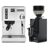 The Rancilio Silvia M V6 Espresso Machine in silver stainless steel, paired with the Eureka Mignon Zero 55s Single Dose Coffee Grinder in matte black, sits against a white background. This stylish bundle by Rancilio promises consistent espresso extraction for your perfect cup.