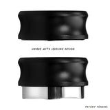 Two black Normcore Gravity Distributor Tools (58.5mm) with metallic bottoms are shown in two positions: the top one retracted and the bottom one extended, illustrating this espresso distribution tool’s unique auto-leveling design. Text: “UNIQUE AUTO LEVELING DESIGN” and “PATENT PENDING.”.