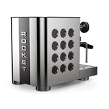Introducing the Rocket Appartamento TCA, a premium domestic espresso machine with flow control and a sleek stainless steel-black finish. It features precise temperature adjustment, circular side holes, a milk frothing wand, and the iconic "Rocket" brand name displayed vertically.