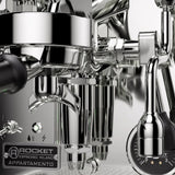 Close-up of the Rocket Appartamento TCA Espresso Machine with Flow Control (RE502A3B12) in stainless steel, ideal for premium homes. Features include a steam wand, pressure gauge, and "Rocket" branding on a plate labeled "Temperature Control Adjustment.