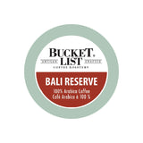 The label for Bucket List's Bali Reserve Single Serve Pods, sold in boxes of 24, features a circular design with a green outer ring and a white inner circle. The text inside reads "BUCKET LIST ARTISAN CRAFTED" at the top, accompanied by the logo, and "COFFEE ROASTERY" below. The red center text highlights "BALI RESERVE 100% Arabica Coffee Café Arabica à 100%," indicating that these single-serve pods are Keurig compatible.