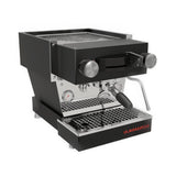 The La Marzocco Linea Mini R Dual Boiler Semi-Automatic Espresso Machine (Black) is a sleek stainless steel and black appliance equipped with a portafilter, steam wand, pressure gauge, and drip tray. It features an advanced workflow system including pre-infusion capabilities and proudly displays the red "La Marzocco" logo on the front lower right corner, accompanied by several control knobs.